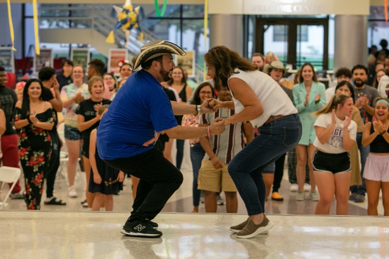A man in a blue shirt dancing with a woman in a white shirt.