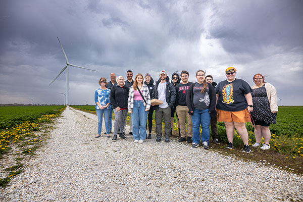 Group of people standing in front of a windmill.
