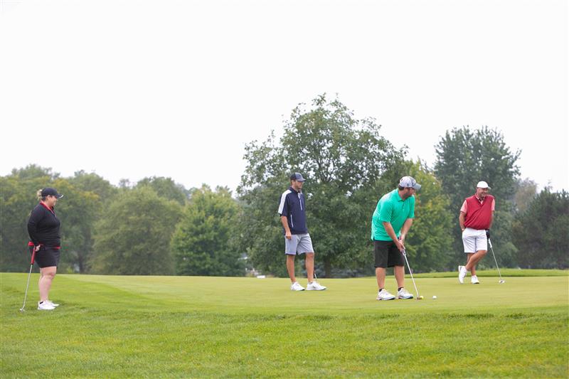 a group of three men and one woman golf.