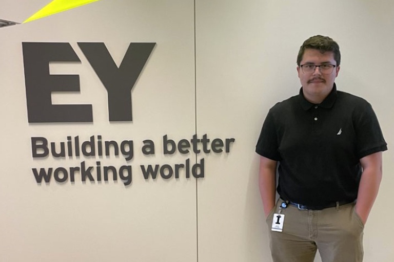 Austin Ramirez standing in front of EY sign.