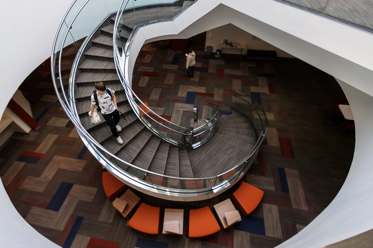 A student walking down the Library staircase.