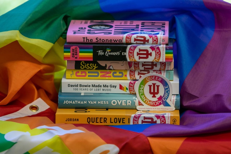 Stack of LGBTQ Books on top of Pride flag.