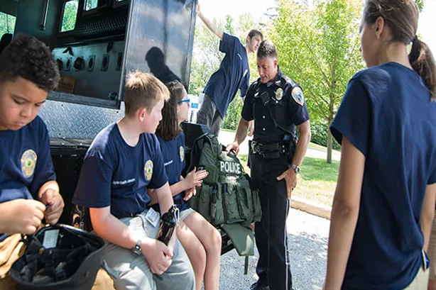 Officer speaking to young kids at camp.