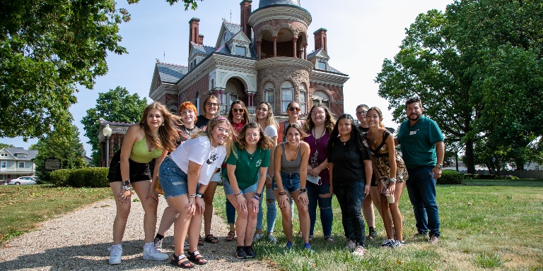 A group of students standing in front of the Seiberling mansion.