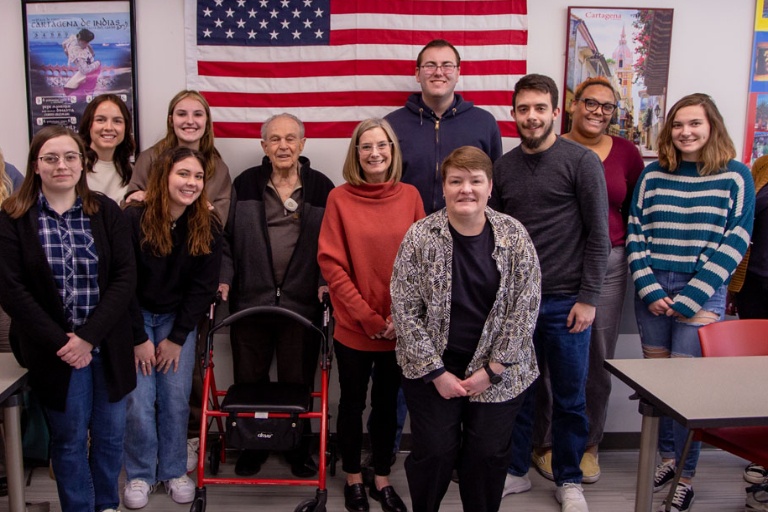 World War II veteran, Cye Zwirn, standing with students and faculty in a classroom.