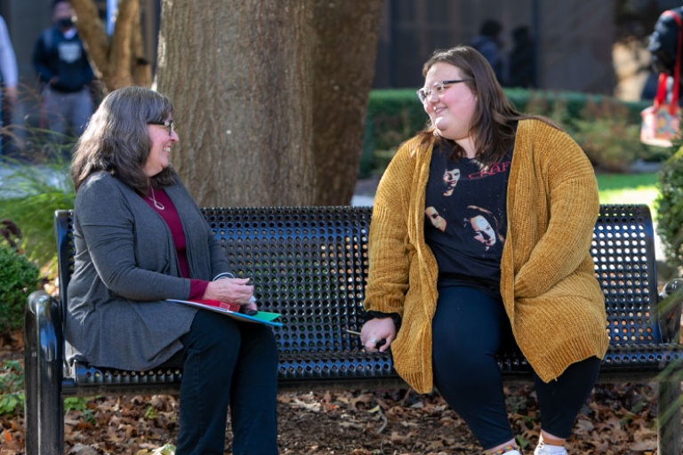 Joann Kaiser, program coordinator and a student sitting on a bench.