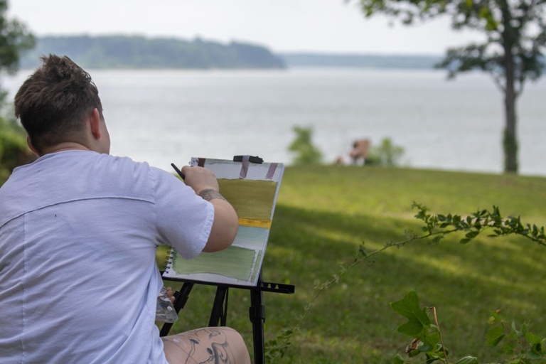 Student Alex Townsend painting outdoor by the water