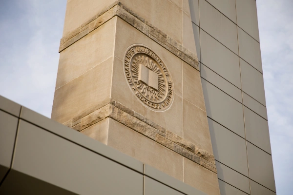 A picture of a stone façade with an emblem of a book and Latin words carved in. 