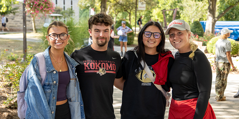 four students at an outdoor IU Kokomo event smiling at the camera.