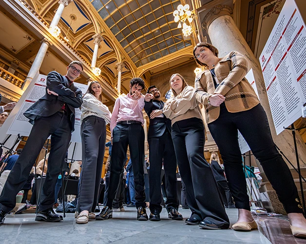 A group of men and women look down and point at a camera. 