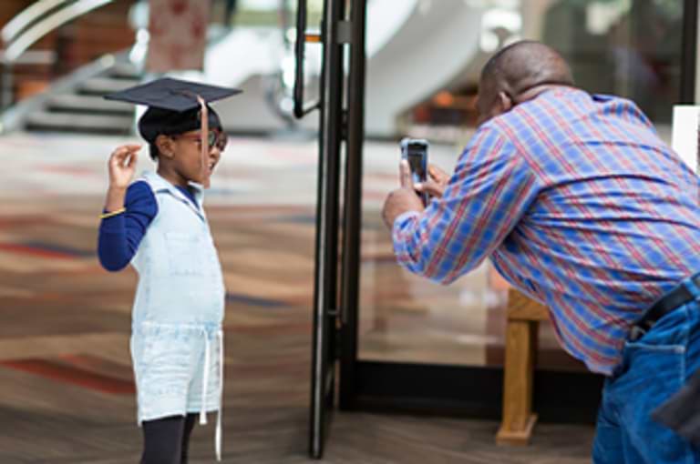 A man taking a photo of a child in a graduation cap