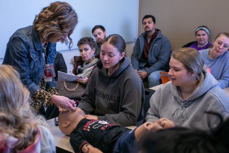 Nursing professor demonstrating NARCAN training, surrounded by students and staff.