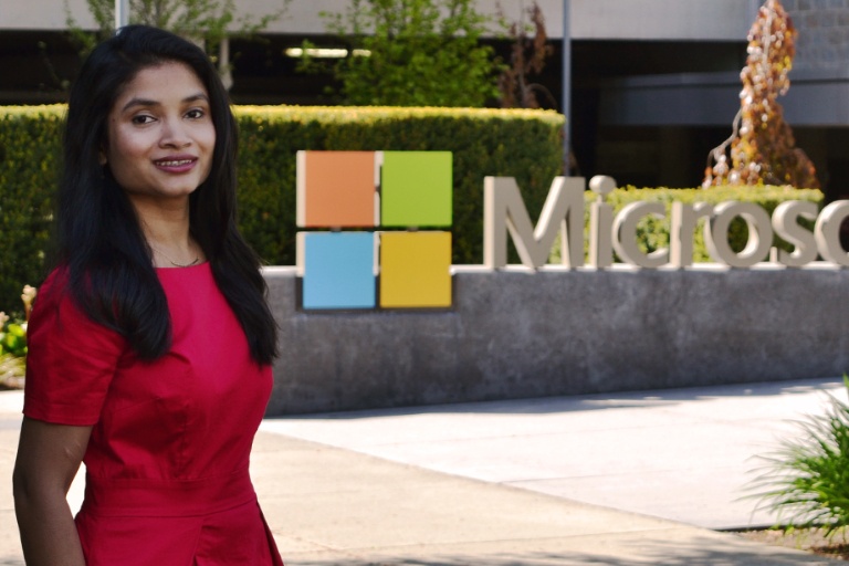 a female student in a red dress standing in front of Microsoft