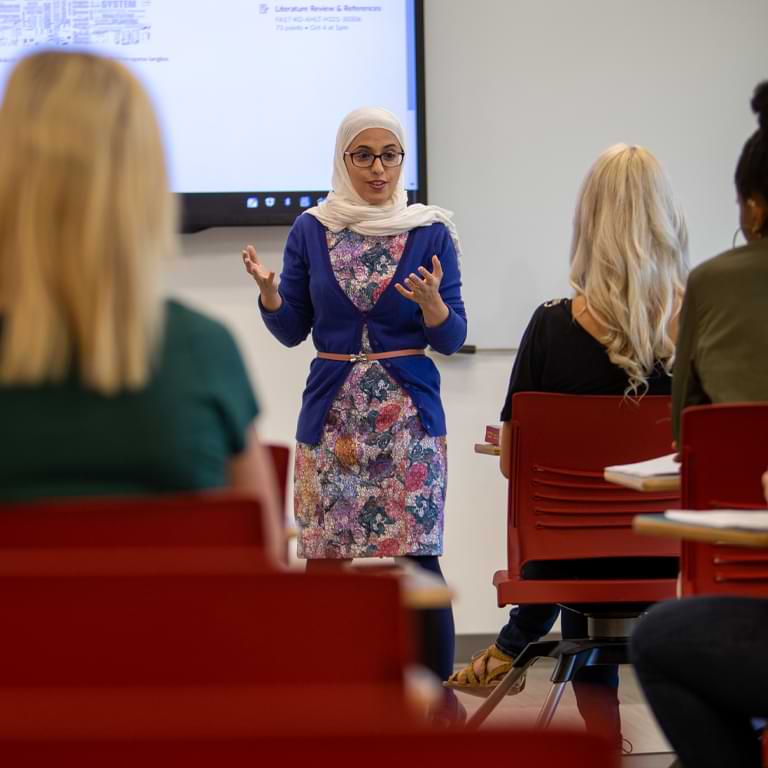 Ghadah Alshuwaiyer in front of a classroom.